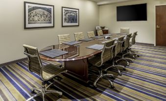 a conference room with a long wooden table and chairs , surrounded by framed pictures on the wall at New Haven Hotel
