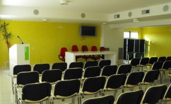 a conference room with rows of chairs arranged in a semicircle , and a television mounted on the wall at Silver Hotel