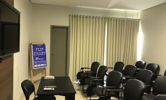 a conference room with a table and chairs , a flip chart , and curtains by the door at Oasis Hotel