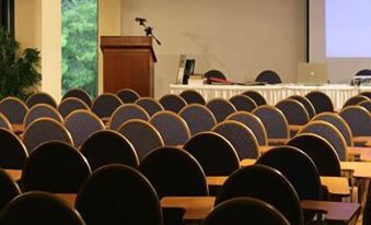 a conference room with rows of chairs arranged in a semicircle , and a projector on the wall at Hotel Antonios