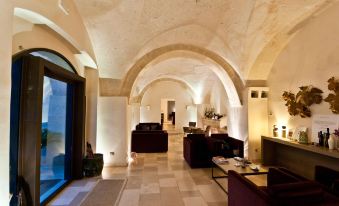 a spacious living room with a curved ceiling , stone walls , and wooden floors , featuring various pieces of furniture and decorations at Masseria le Fabriche