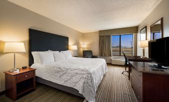 a large bed with a white and black comforter is in the middle of a room with a window at Best Western Park Oasis Inn