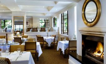 a large dining room with multiple tables , chairs , and a fireplace , all set for a formal dinner at Peppers the Hills Lodge