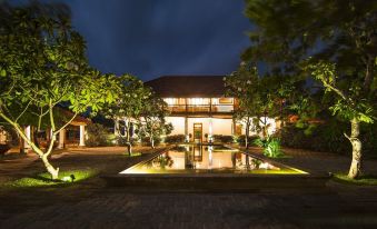 a large house with a well - lit courtyard and a pool is surrounded by trees at night at Uga Ulagalla - Anuradhapura