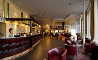 a hotel lobby with a reception desk , couches , and chairs arranged in a modern and stylish setting at Scandic Ishavshotel