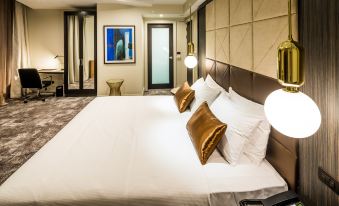 a large bed with white sheets and two brown pillows is in a room with a framed picture on the wall at DoubleTree by Hilton Wellington