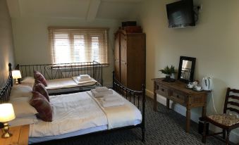 a bedroom with a bed , dresser , and tv , featuring white bedding and a window with curtains at The Hollies Inn