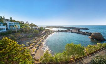 a beach scene with a large group of people enjoying their time at the shore at Iberostar Selection Creta Marine