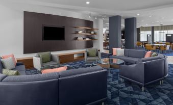 a modern lounge area with blue couches , chairs , and tables arranged in a cozy setting at Courtyard Tampa Oldsmar