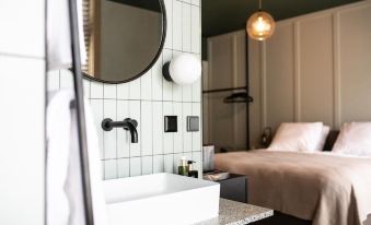 a bathroom with a sink , mirror , and towel rack is shown next to a bed at Mr Lewis Zandvoort