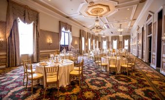 a large banquet hall with multiple tables set for a formal event , featuring gold chairs and white tablecloths at Bourbon Orleans Hotel