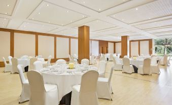 a large banquet hall with white tables and chairs , all set for a formal event at Abba Garden