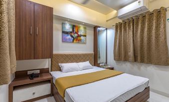 a clean and well - organized hotel room with a comfortable bed , a tv , and a bathroom at Hotel Rajlaxmi Grand