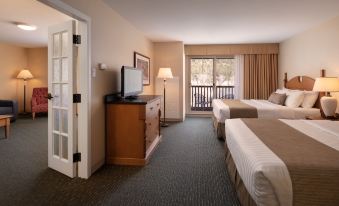 a hotel room with two beds , a tv , and a door leading to a balcony at St. Eugene Golf Resort & Casino