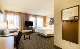 a modern hotel room with a bed , desk , and window , along with a television and other amenities at Staybridge Suites Milwaukee Airport South