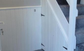 a white door with a handle and lock is in a room next to a wooden door at Laburnum Cottage Guest House