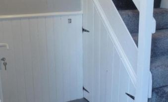 a white wooden door with a handle and a doorknob , situated in a room with white walls and a staircase at Laburnum Cottage Guest House