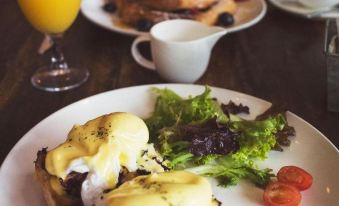 a dining table with a plate of eggs benedict and a cup of coffee on it at The Greyhound Hotel