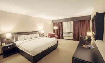 a large bed with white linens is in a room with a desk , chair , and lamp at Casino Queen Hotel