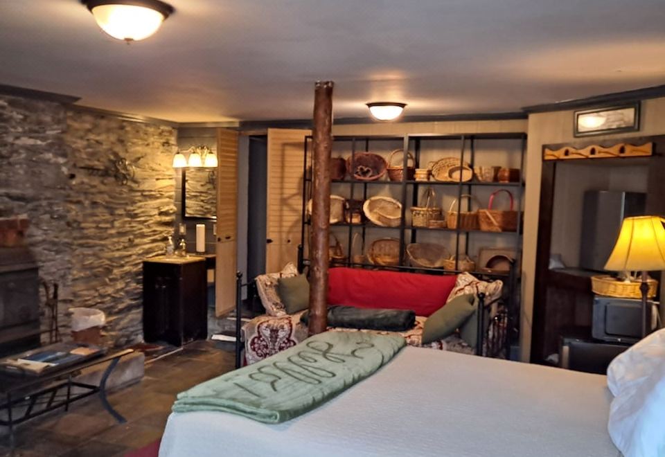 a cozy living room with a fireplace , stone wall , and a comfortable bed in the background at Town's Inn