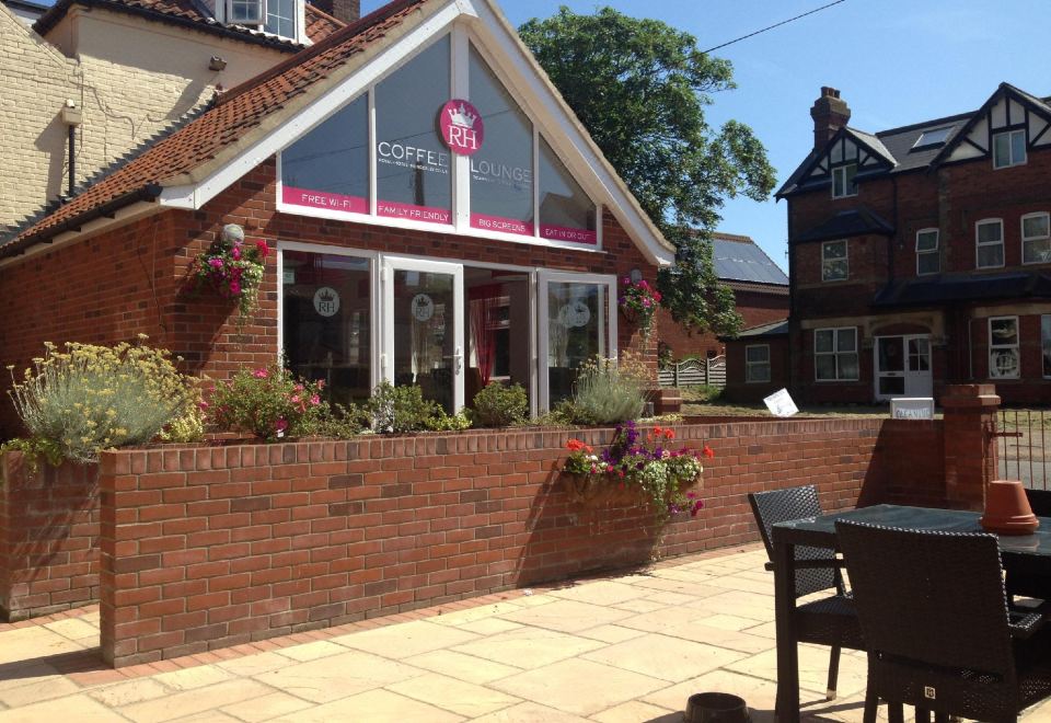 a brick building with a red sign on the front , surrounded by a paved courtyard at The Royal Hotel