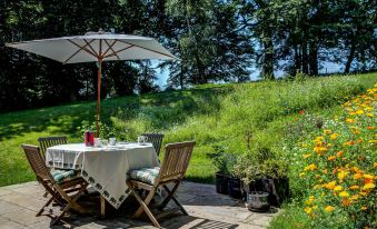 a table with a white tablecloth and chairs is set up on a patio surrounded by greenery at South Park Farm Barn