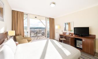 a hotel room with a large bed , a tv , and a balcony overlooking the ocean at Holiday Inn Leeds - Brighouse