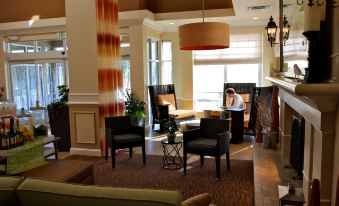 a hotel lobby with two chairs and a fireplace , creating a warm and inviting atmosphere at Hilton Garden Inn Albany