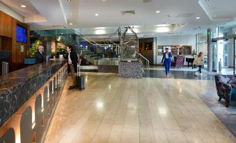 a man and a woman with luggage are standing in a large , well - lit room at Crowne Plaza Dublin - Blanchardstown