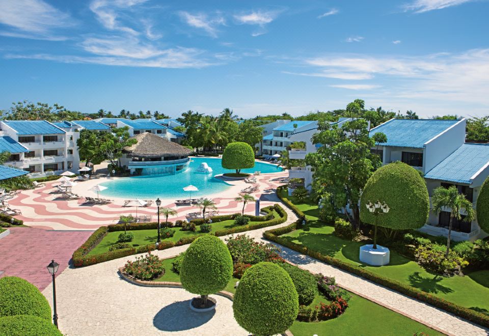a large resort with a pool surrounded by lush greenery and a view of the ocean at Sunscape Puerto Plata All Inclusive