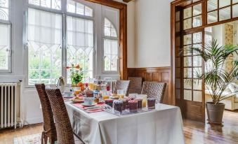 a dining room with a table set for breakfast , surrounded by chairs and a large window at La Maison Rouge Broceliande
