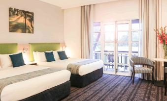 a hotel room with two beds , a chair , and sliding glass doors leading to an outdoor balcony at Novotel Swan Valley Vines Resort