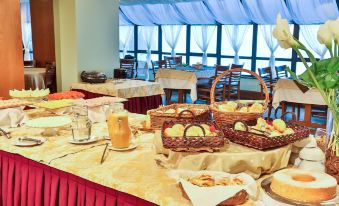 a dining table with a variety of food items , including breads , pastries , and drinks , arranged for a meal at Hotel Home Green Home