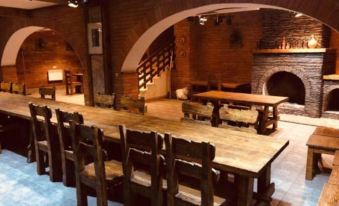 a large wooden dining table surrounded by chairs in a room with brick walls and a fireplace at Orion Hotel