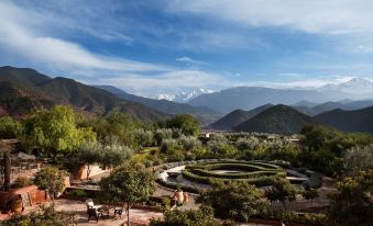 a beautiful garden with a winding path , surrounded by trees and mountains in the background at Kasbah Bab Ourika