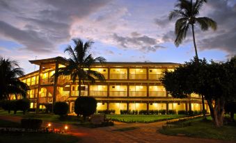 a large hotel with multiple floors and balconies , surrounded by palm trees and lit up at night at Fiesta Resort All Inclusive Central Pacific - Costa Rica