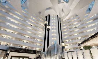 a large , modern building with a high ceiling and large windows , surrounded by glass walls and black and white columns at Crown Metropol Perth