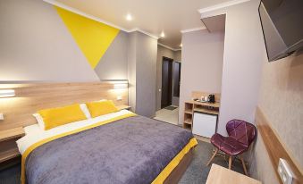 a modern bedroom with a purple and yellow bedspread , a wooden headboard , and a desk area at Luna Hotel
