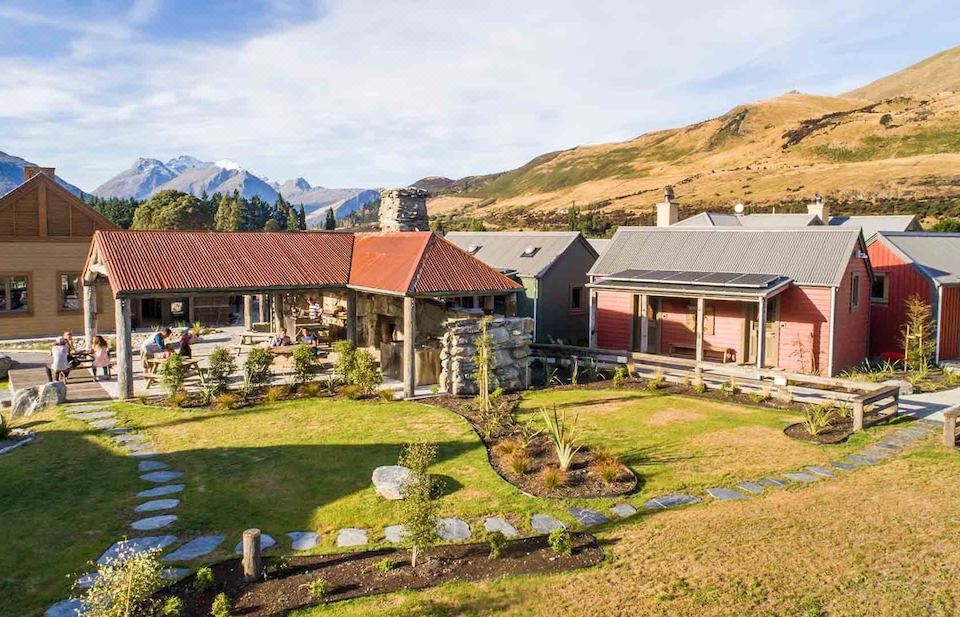 a large house surrounded by grass and trees , with a mountainous landscape in the background at The Headwaters Eco Lodge