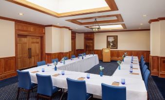 a large conference room with multiple long tables set up for a meeting , each table having blue chairs and white tablecloths at Historic Boone Tavern
