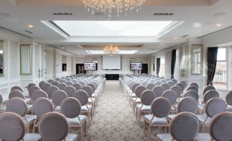 a large conference room with rows of chairs arranged in a semicircle , and a projector screen on the wall at Rockliffe Hall Hotel Golf & Spa