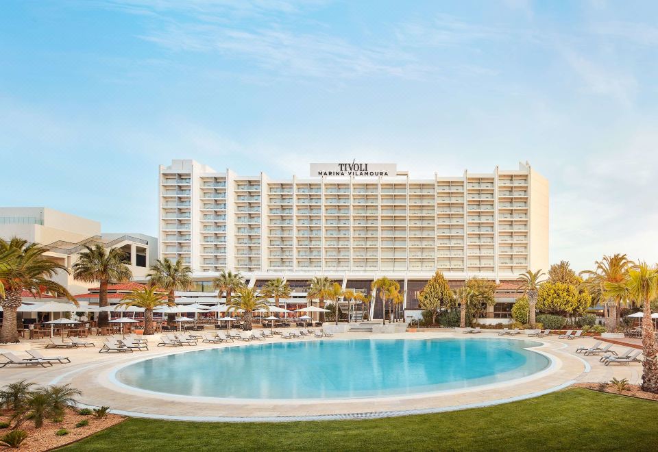 a large hotel with a swimming pool in front of it , surrounded by palm trees at Tivoli Marina Vilamoura