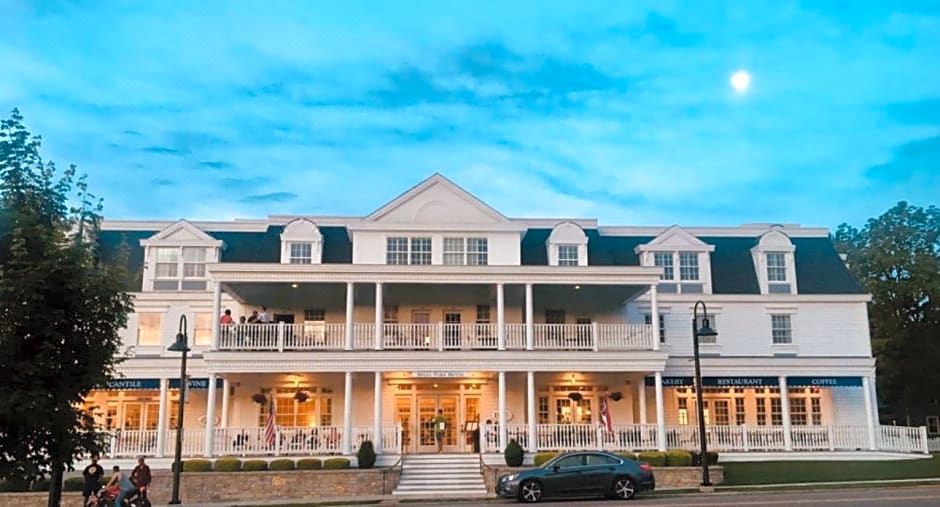 a large , two - story white building with multiple floors and balconies , surrounded by trees and people at Mills Park Hotel