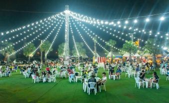 a large outdoor event with numerous people gathered on a grassy field , enjoying the night sky and enjoying the ambiance at Venice Resort
