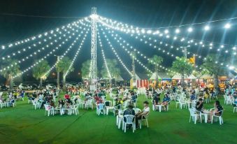 a large group of people gathered in a grassy area , with many of them sitting on white chairs at Venice Resort