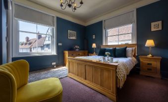 a large bed with a wooden headboard is situated in a bedroom with blue walls and purple carpet at The Swan Inn