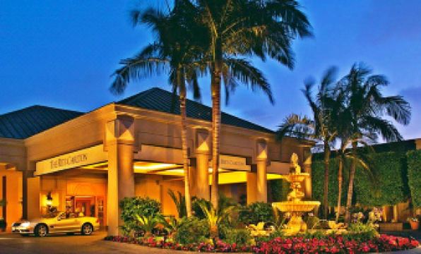 a large hotel with a fountain in front of it , surrounded by palm trees and flowers at The Ritz-Carlton, Marina del Rey