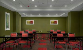 a conference room with green walls and red chairs arranged in rows , ready for a meeting or event at Home 2 Suites by Hilton Muskogee