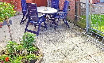 a patio with a dining table and chairs set up for outdoor dining , surrounded by greenery at Gila