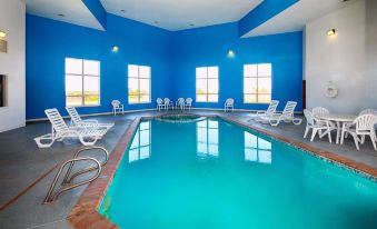 an indoor swimming pool with a blue and white color scheme , surrounded by white lounge chairs at LaJunta Inn